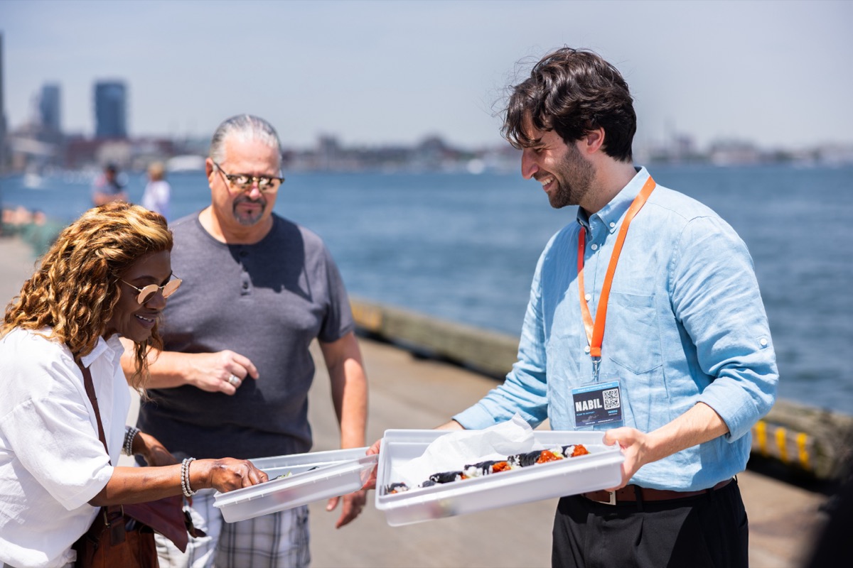 Nabil handing guests a tray of sushi on Boston's waterfront during the seafood tour